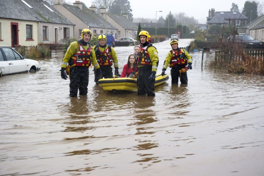 Woman in recue boat being led through flooded Comroe street