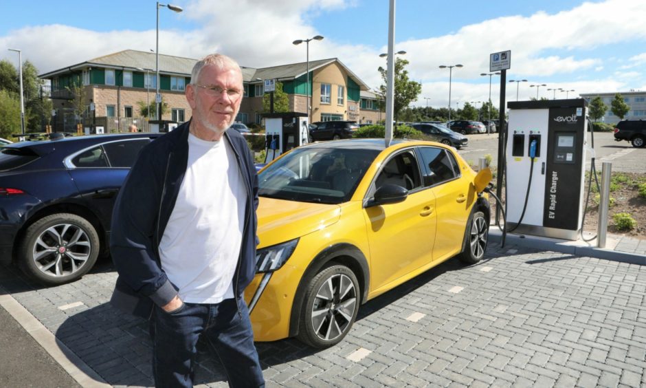 Mike Devine poses before charging his EV in Forfar