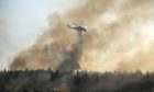 An helicopter drops water over a fire in Varibobi area, northern Athens, Greece, Wednesday, Aug. 4, 2021. Firefighting planes were resuming operation at first light Wednesday to tackle a major forest fire on the northern outskirts of Athens which raced into residential areas the previous day, forcing thousands to flee their homes amid Greece's worst heatwave in decades. AP Photo/Thanassis Stavrakis