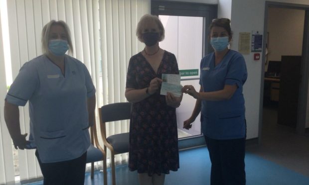 Rona Nicolson, president of Silvie and Ruthven SWI, presents £500 cheque to PRI staff in memory of Jackie McCowan.