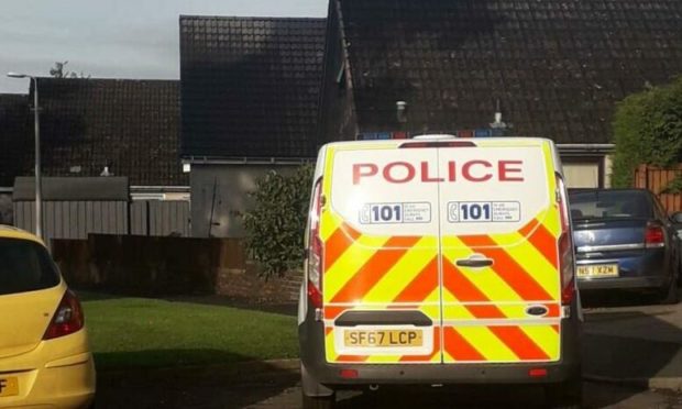 A police van sits outside the property in Kirriemuir where a woman took ill during a drugs bust