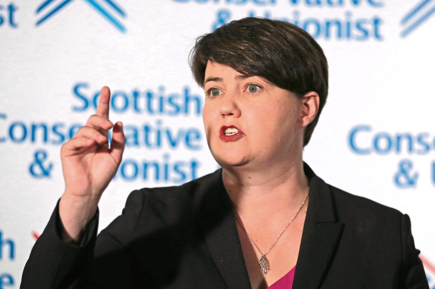 Former leader of the Scottish Conservatives Ruth Davidson speaking in front of a Scottish Conservative and Unionist background.