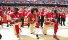 San Francisco 49ers quarterback Colin Kaepernick (c) along with Eli Harold (l) Eric Reid (r) take a knee during the US national anthem.