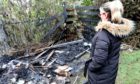 Rosey Cunningham looks at the damage to her shed and playshed which was set on fire in the early hours of the morning in her back garden.