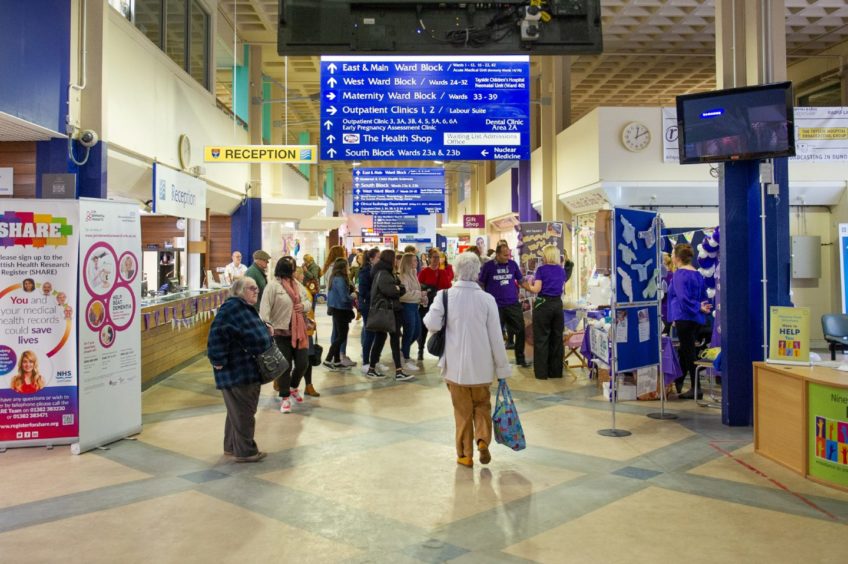 Busy concourse at Ninewells Hospital in Dundee showing patients and staff coming and going in front of the reception desk.