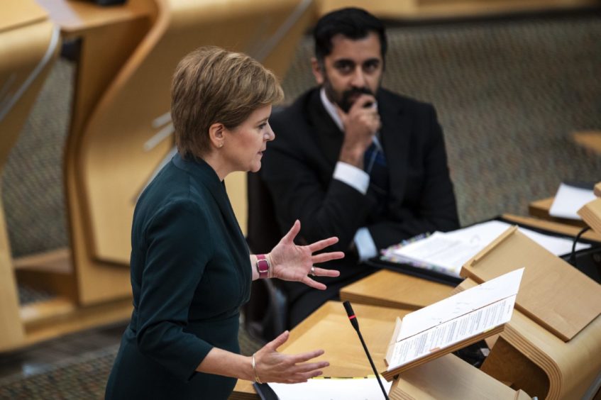 Humza Yousaf seated next to Nicola Sturgeon in the Scottish parliament.