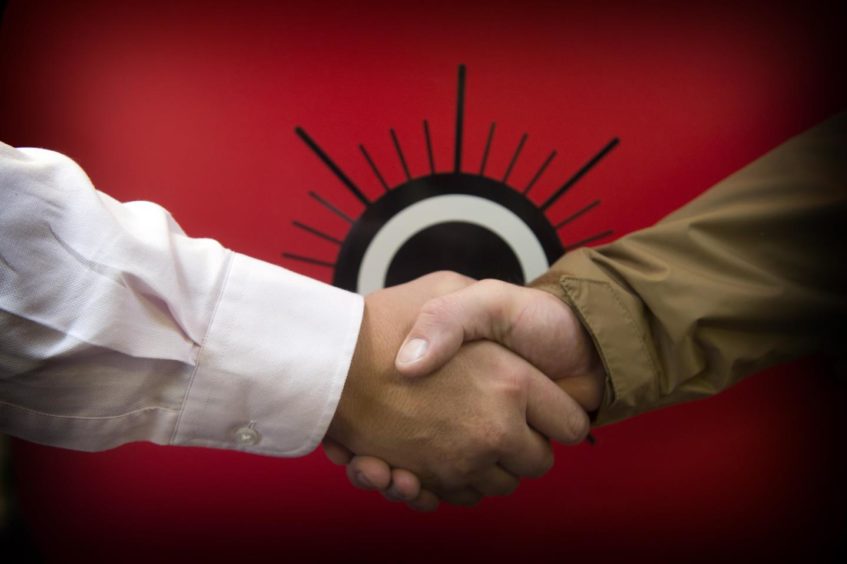 Two people shaking hands in front of the Poppyscotland logo