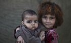 Afghan refugee girl, Khalzarin Zirgul, 6, holds her cousin, Zaman, 3 months, as they pose for a picture, while playing with other children in a slum on the outskirts of Islamabad, Pakistan