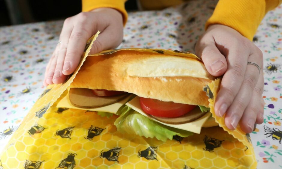 A yellow beeswax wrap containing a sandwich.