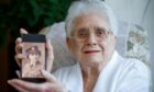 99-year-old Mrs Margaret Overend with a photo of herself in the Second World War