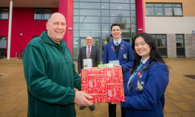 Grove Academy has already given a cash donation to Dundee and Angus Foodbank and will make a food donation this week. Pictured are pupils Angie Liu and Monty Monteith and rector Graham Hutton with foodbank manager Ken Linton.