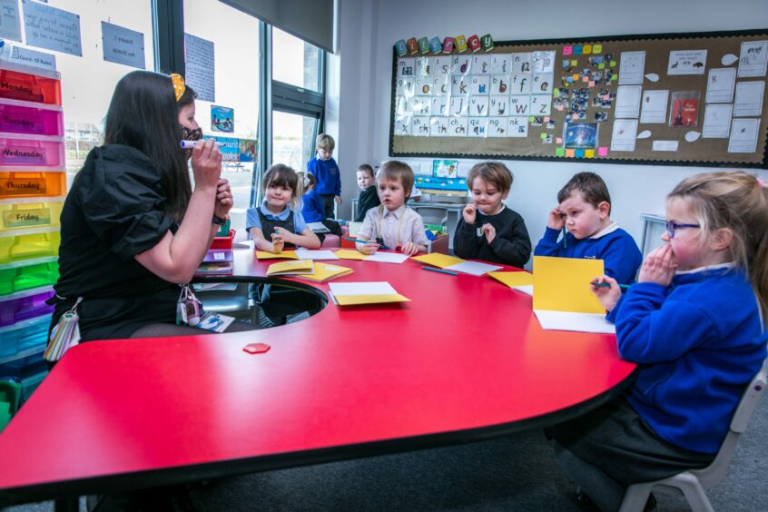 Children from Longhaugh Primary sit with their teacher on their first day back after lockdown 2021