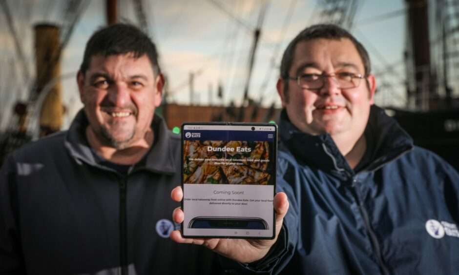 Lochlan Cox and Jamie McPhee holding the Dundee Eats app.