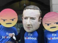 A Mark Zuckerberg figure with people in angry emoji masks outside Portcullis House in Westminster (PA)