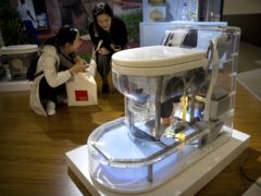Visitors look at a model of a self-contained toilet at the Reinvented Toilet Expo in Beijing (Mark Schiefelbein/AP)