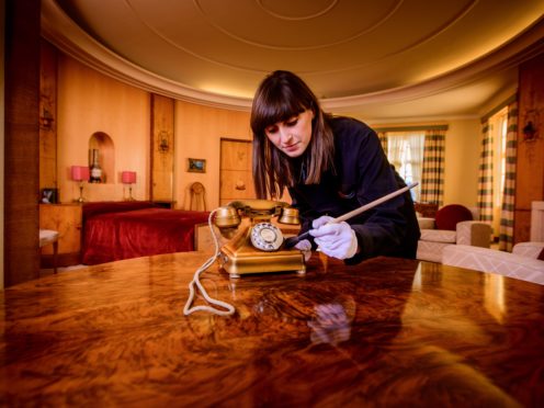 English Heritage Collections curator Olivia Fryman gives a recently donated 1930s gold telephone a final brush up before it goes on public display for the first time at Eltham Palace (English Heritage)