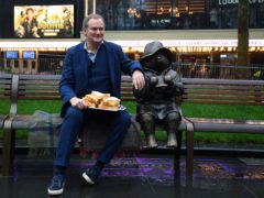 Hugh Bonneville poses with marmalade sandwiches next to the Paddington statue (Victoria Jones/PA)