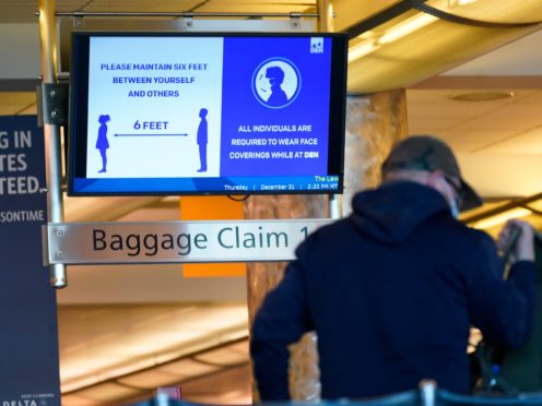An electronic sign advises travellers to wear face masks and practice social distancing while passing through the main terminal of Denver International Airport (David Zalubowski/AP)