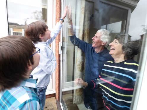Ben and Isaac talk to their grandparents Sue and Alan through a window at their home in Knutsford, Cheshire (PA)