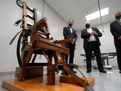 Virginia governor Ralph Northam, left, looks over the electric chair in the death chamber at Greensville Correctional Centre with Operations Director, George Hinkle, center, and Warden Larry Edmonds, right, prior to signing a bill abolishing the death penalty (Steve Heiber/AP)