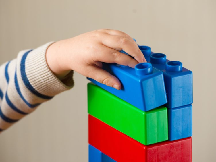 A preschool age child plays with plastic building blocks (PA)
