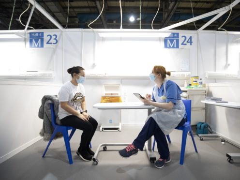 Nurse Eleanor Pinkerton speaks with one of the health and social care staff before administering a coronavirus vaccine (PA)