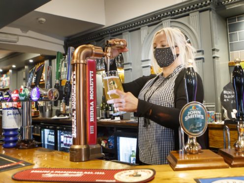 Melanie Scott pulling a pint at the Black Bull pub in Haworth, West Yorkshire (PA)