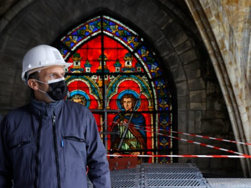 French President Emmanuel Macron stands by a stained glass window under the damaged vaults during a visit at the reconstruction site of the Notre-Dame de Paris cathedral, Thursday April 15, 2021. Two years after a fire tore through Paris’ most famous cathedral and shocked the world, French President Emmanuel Macron on Thursday visited the building site that Notre Dame has become to show that French heritage has not been forgotten despite the coronavirus. (Ian Langsdon, Pool via AP)