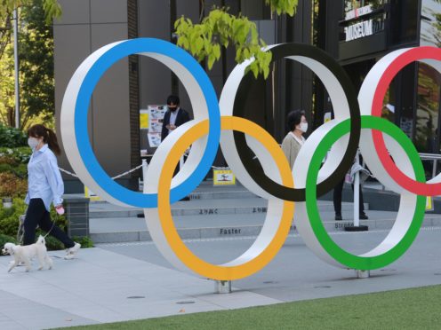 A woman with her dog walks past the Olympic rings in Tokyo (Koji Sasahara/AP)