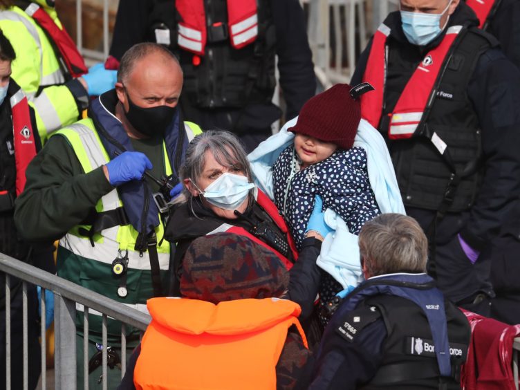 A young girl amongst a group of people thought to be migrants is carried by a Border Force officer as they are brought in to Dover, Kent (Gareth Fuller/PA)