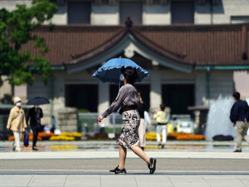 A woman wearing a protective mask to help curb the spread of the coronavirus walks at a park in Tokyo (Eugene Hoshiko/AP)