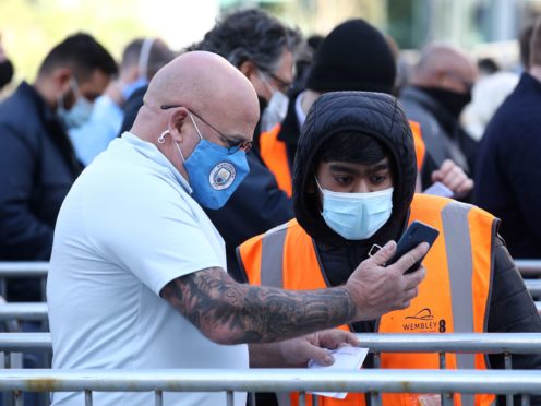 A Manchester City fan shows a Covid-19 test result to a steward outside the Wembley stadium ahead of the Carabao Cup Final (Gareth Fuller/PA)