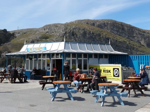 People sit outside a bar in Llandudno, Wales, where lockdown restrictions have eased (Peter Byrne/PA)