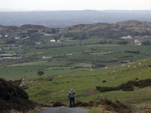 A man looks across the border between the Republic of Ireland and Northern Ireland from Edentober in Co Louth to Newry in Co Down.