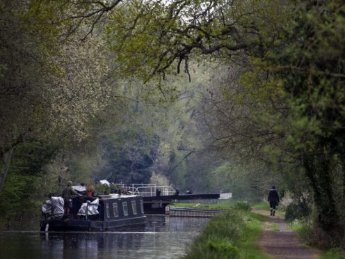 A canal boat travels in the rain along the River Kennet near Theale, Berkshire (PA)