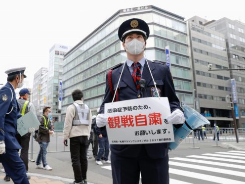 A security guard stands with a note calling for refraining from watching a half-marathon in Sapporo (Kyodo/AP)