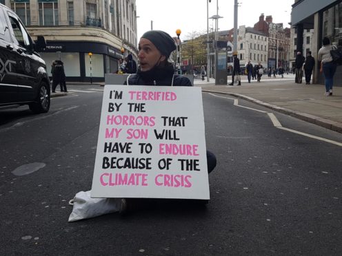 A climate protester blocks Wheeler Gate in Nottingham city centre(Diana Schmies/PA)