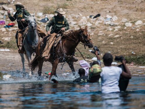 US Customs and Border Protection mounted officers attempt to contain migrants as they cross the Rio Grande (AP Photo/Felix Marquez)