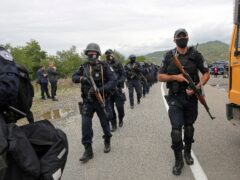 Kosovo police officers walk to replace their colleagues near the northern border crossing of Jarinje (Visar Kryeziu/AP)