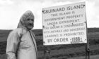 Malcolm Broster of MOD Chemical Defence Establishment at Porton Down, alongside one of the warning signs on Gruinard Island.
