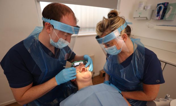 Dentist Dr. Allan Clarke and Dental Nurse Lynsey Galaway (right) wearing PPE with fellow dentist Dr. Danielle Magee to show new social distancing procedures at a practice in Belfast.