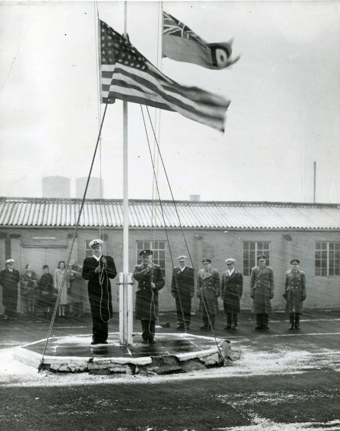 Military officials stand to attention in poor weather for the raising of the flags at the opening of the RAF base in Edzell in 1960.