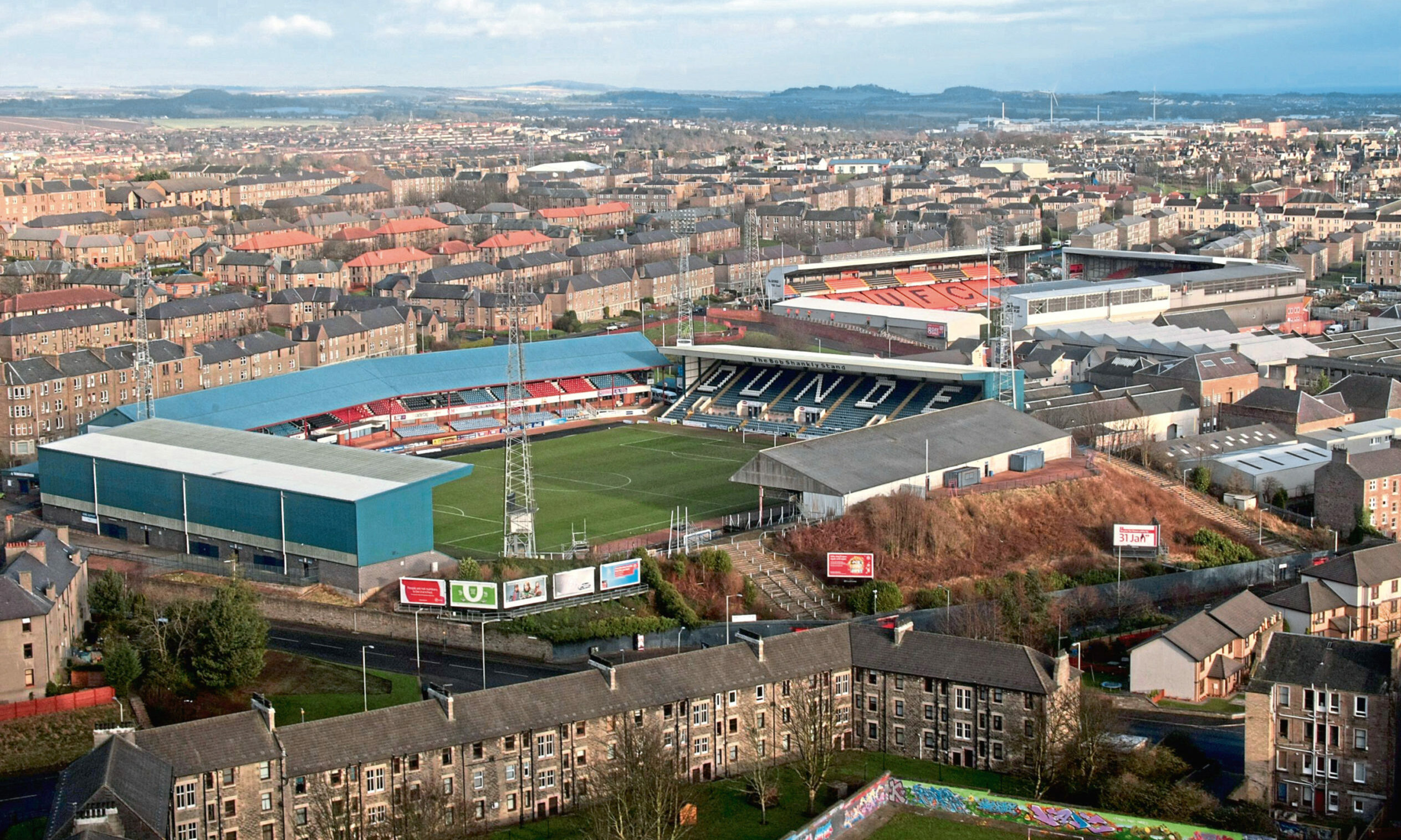 Photo shows the Dundee skyline with the neighbouring football grounds of Tannadice and Dens Park, home to Dundee United and Dundee football clubs, in the centre.