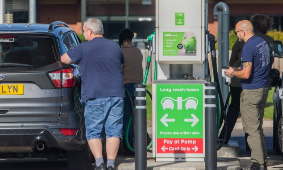 People fill up their cars at petrol pump.