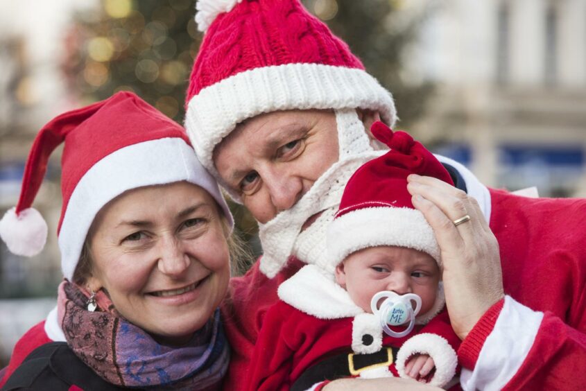 Three people including a baby in Santa outfits for the Dundee Santa Dash