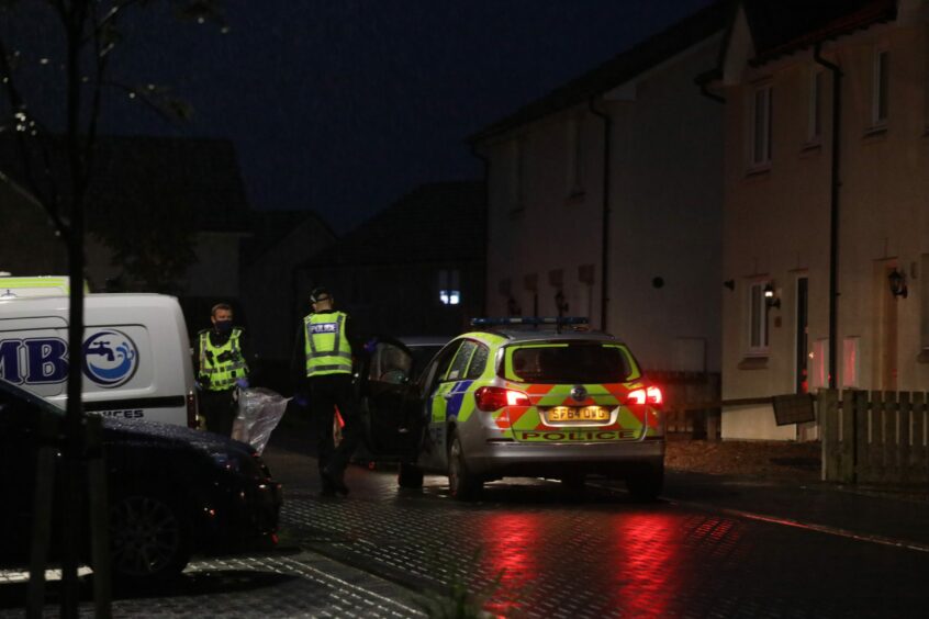 A police car and two officers on a dark street in Monifieth after a possible unexploded device was found