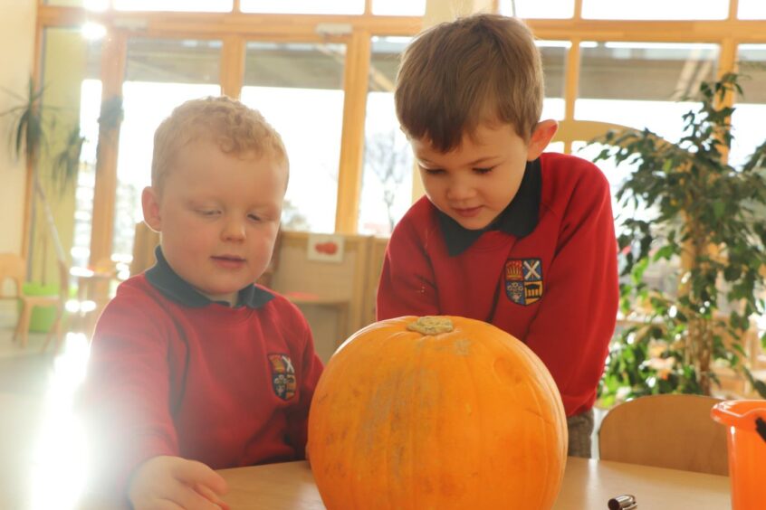 Two children in High School of Dundee Nursery and a pumpkin