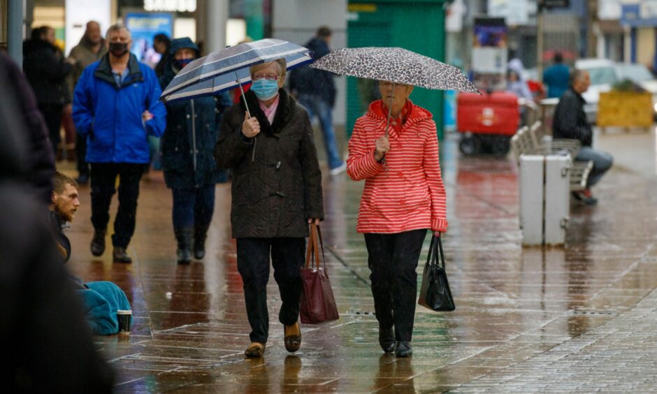 People walking with umbrellas up in Kirkcaldy town centre during heavy rain