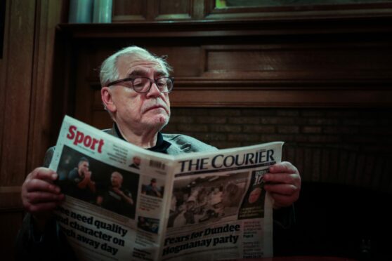 Brian Cox reads a copy of The Courier