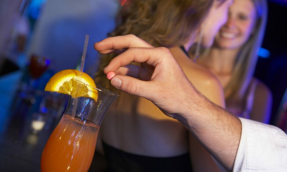 A person spiking a drink in a nightclub.